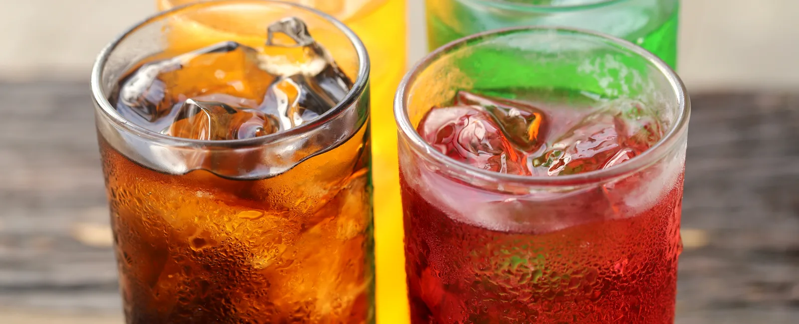 Colorful cold drinks with ice on a wooden table