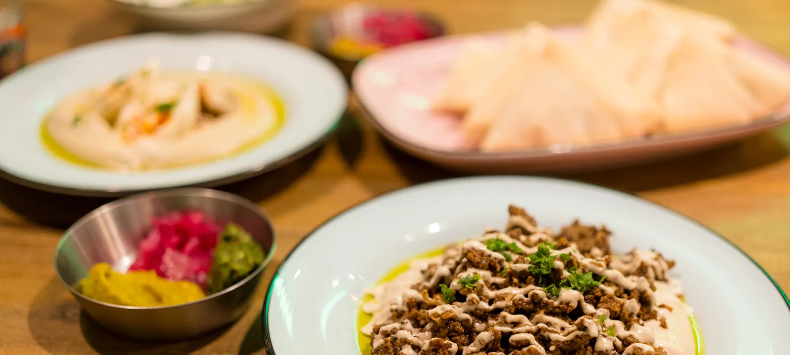 Hummus plate topped with meat and served with pita