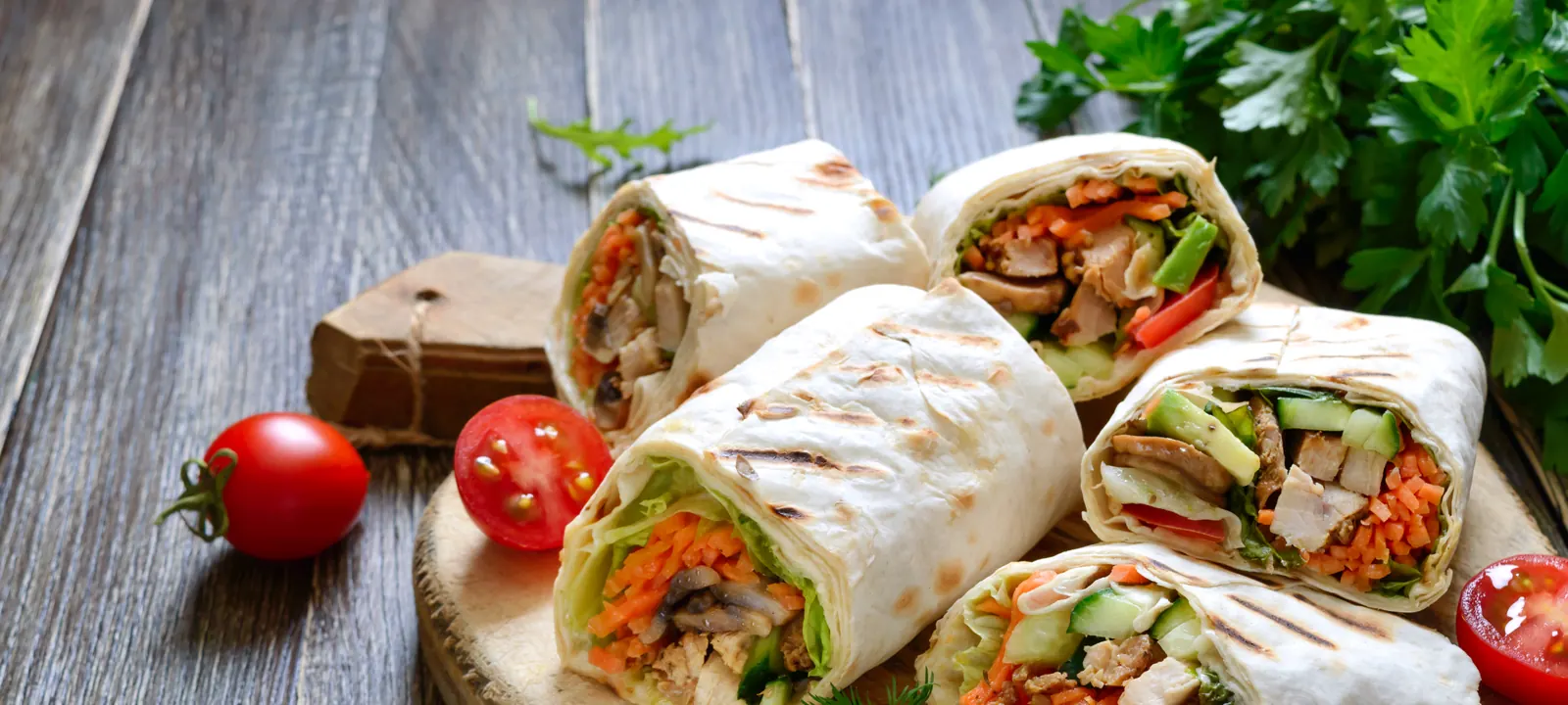 Fresh chicken wraps with vegetables on a wooden board