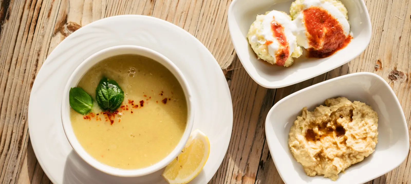 Soup and Middle Eastern meze dishes on a wooden table